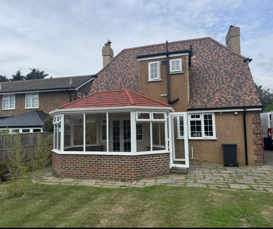 White uPVC conservatory with a tiled solid roof on a detached house